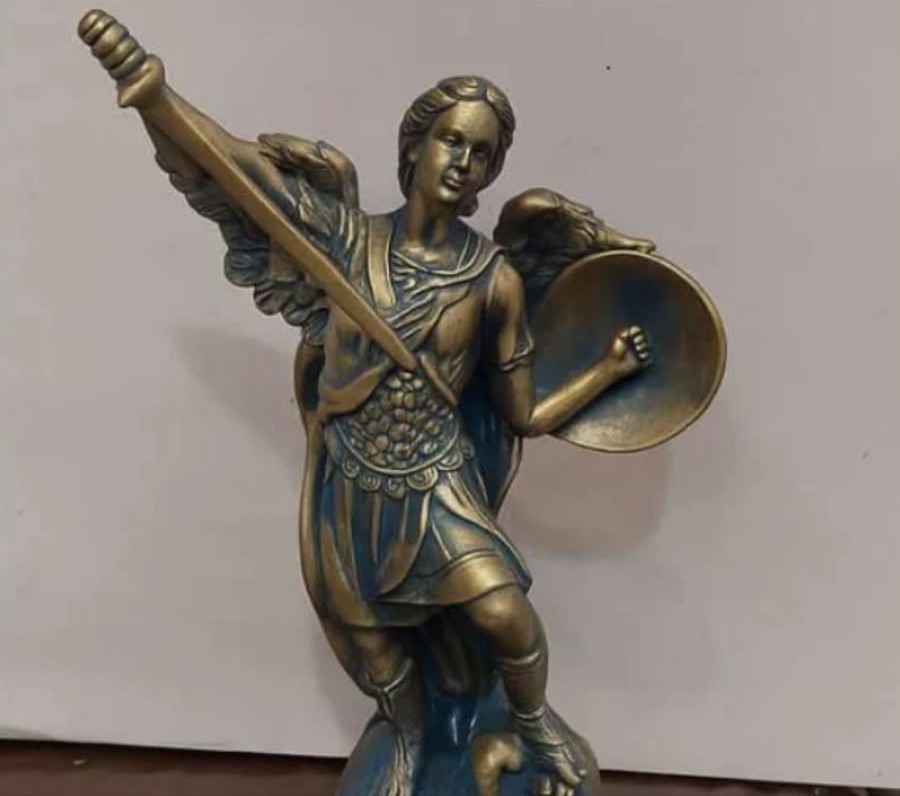 Estátua de São Miguel Arcanjo pintada em tons de ouro velho, empunhando a espada erguida e um escudo